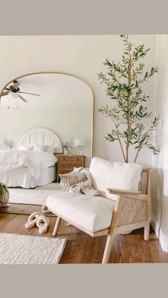 a living room with white furniture and a tree in the corner near a mirror that has been placed on the floor