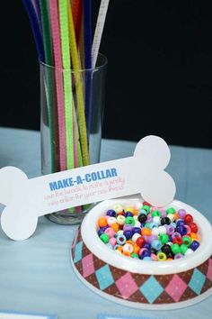 a bowl filled with lots of colorful candy next to a cup full of straws