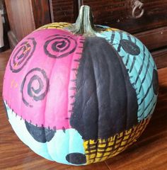 a painted pumpkin sitting on top of a wooden table