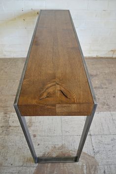 a wooden bench sitting on top of a floor next to a white brick wall in a room