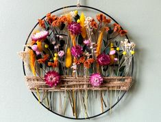 an arrangement of flowers arranged on a circular wire wall art piece hanging on the wall