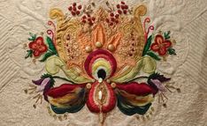 a close up of a piece of cloth with flowers and leaves on it, in the shape of a peacock