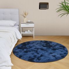 a bed room with a neatly made bed and a blue round rug on the floor