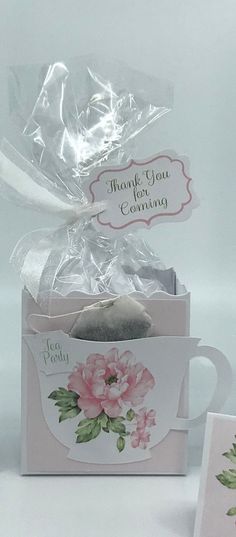 a tea bag in a gift box next to a card with a flower on it