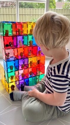 a little boy sitting on the floor playing with some colorful blocks