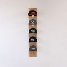 the hat rack is made out of wood and has five hats on it