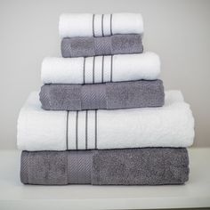 five folded towels stacked on top of each other in white and grey colors with black stripes