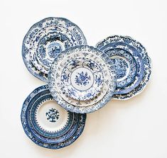 four blue and white plates stacked on top of each other in the shape of flowers