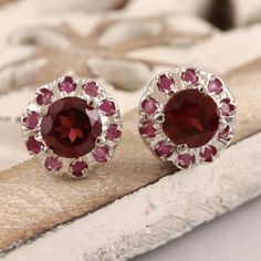 Harmonious pink and red gems come together on Bhavya Jain small but stunning stud earrings. The artisan crafts the earrings from rhodium-plated sterling silver, centering the pair with a single faceted garnet stone. A ring of deep pink rubies circle the garnet with sparkling beauty. Ruby Earrings For Valentine's Day, Wedding Earrings With Lab-created Ruby Gemstone, Red Sterling Silver Fine Jewelry, Nickel-free Ruby Jewelry For Gifts, Nickel-free Ruby Jewelry Gift, Round Gemstone Cluster Earrings For Anniversary, Ruby Jewelry With Matching Earrings For Gift, Ruby Jewelry With Matching Earrings As A Gift, Ruby Jewelry Set With Matching Earrings As A Gift