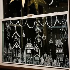 a window with christmas decorations drawn on it in front of a star hanging from the ceiling