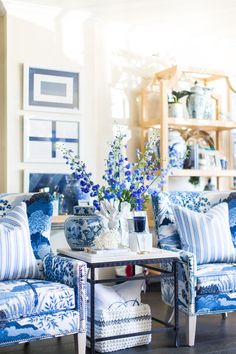 a living room with blue and white furniture in the center, vases filled with flowers