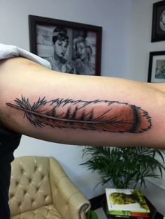 a man's arm with a feather tattoo on it