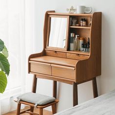 a wooden dressing table with a mirror and stool in front of it next to a window