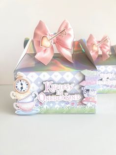 two boxes with pink bows on them sitting next to each other in front of a white wall