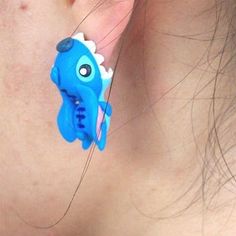 a close up of a person's ear with a blue toy in the shape of an elephant