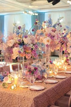 a long table with many vases filled with flowers and candles on top of it