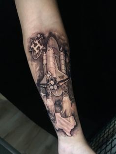 a man with a tattoo on his arm holding a space shuttle in the middle of his arm