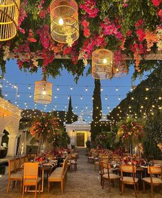 an outdoor dining area decorated with flowers and hanging lights for the party guests to enjoy