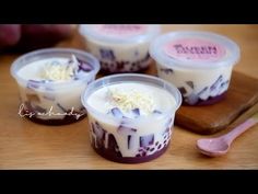 four desserts in plastic cups on a wooden table