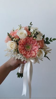 a bridal bouquet being held by a person with white and pink flowers on it