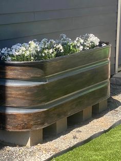 a large metal planter filled with flowers on the side of a home's house