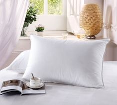 a white pillow sitting on top of a bed next to an open book