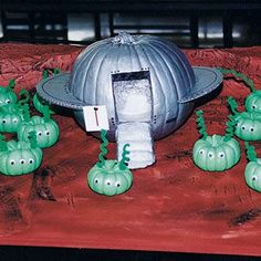 some green plants are growing in front of a silver object on a red table cloth