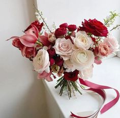 a bouquet of flowers sitting on top of a window sill next to a ribbon