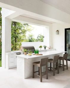 an outdoor kitchen with bar stools next to it