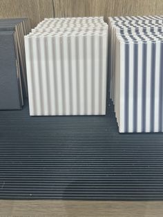 three white and gray boxes sitting on top of a wooden table next to each other