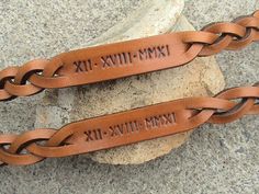 two personalized leather bracelets sitting on top of a rock