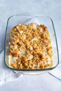 a casserole dish with meat and cheese in it sitting on a white cloth