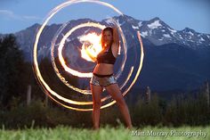 a woman is spinning a fire ring around her body