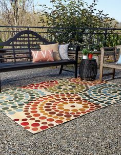 an outdoor area with a bench, rug and potted plants