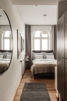 a bedroom with a bed, mirror and rug on the floor in front of it