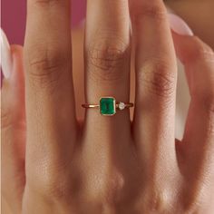 a woman's hand with a ring on it and a green stone in the middle