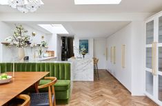 a green couch sitting in the middle of a room next to a wooden dining table