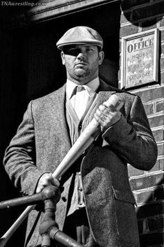 a man in a suit and hat holding a baseball bat on the steps of a building