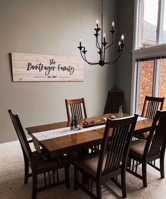 a dining room table with wooden chairs and a sign on the wall above it that says,