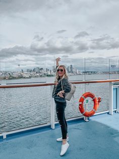 a woman standing on the deck of a boat waving at the camera with her hand in the air