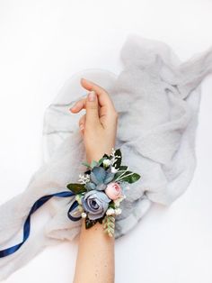 a woman's arm with flowers on it and a blue ribbon around the wrist