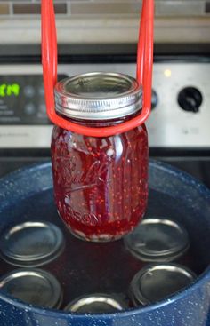 a mason jar filled with red liquid sitting on top of an oven