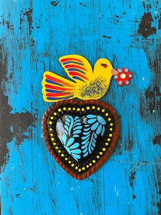 a painted bird sitting on top of a wooden heart