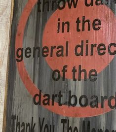 a wooden sign that reads throw darts in the general direction of the dartboard thank you the money