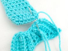 two blue crocheted mitts sitting next to each other on a white surface