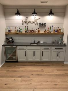 a kitchen with white cabinets and wooden floors, lights above the sink and below the counter