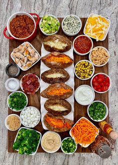 a wooden tray topped with lots of different types of food next to bowls of sauces and condiments