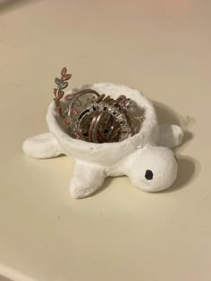 a white turtle with a bunch of rings in it's mouth sitting on a table