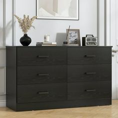 a black dresser sitting in front of a white wall