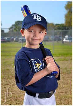 a young boy holding a baseball bat on top of a field in a blue shirt